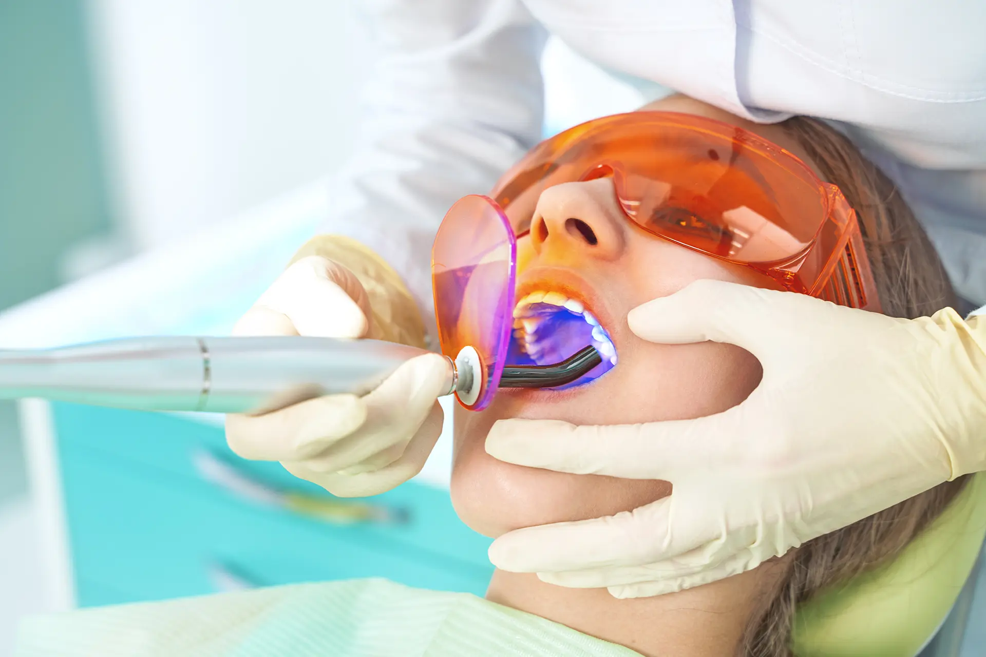 Kompositzahnfüllung wird durch den Zahnarzt mittels Polymerisationslampe ausgehärtet (Symbolbild für Ästhetische Zahnerhaltung im Seitenzahnbereich)